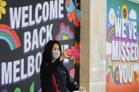 A woman takes a selfie in front of signage in Melbourne, Australia, Wednesday, Oct. 28, 2020. Australia’s second largest city of Melbourne which was a coronavirus hotspot emerges from a nearly four-months lockdown, with restaurants, cafes and bars opening and outdoor contact sports resuming on Wednesday. (AP Photo/Asanka Brendon Ratnayake)