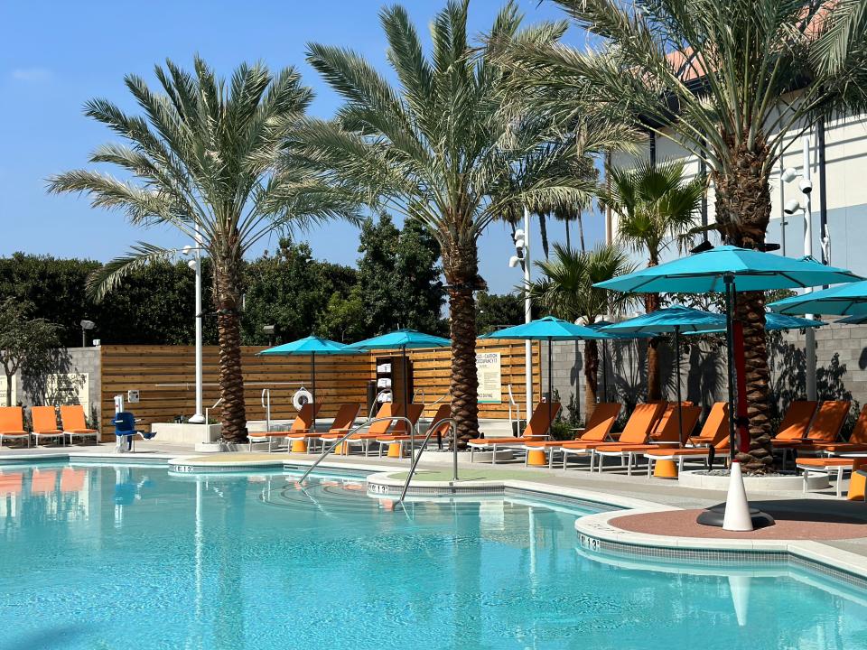 Pool surrounded by orange lounge chairs and palm trees