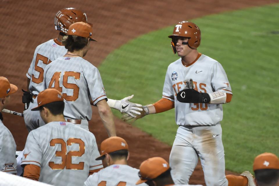 Texas outfielder Eric Kennedy (30) greets teammates after scoring against Mississippi State during the 2021 College World Series at TD Ameritrade Park.