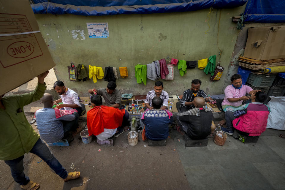 Barbers attend to customers on a pavement at a wholesale vegetable market in Guwahati, India, Wednesday, Feb. 1, 2023. Indian Prime Minister Narendra Modi's government ramped up capital spending by a substantial 33% to $122 billion in an annual budget presented to Parliament on Wednesday, seeking to spur economic growth and create jobs ahead of a general election next year. (AP Photo/Anupam Nath)