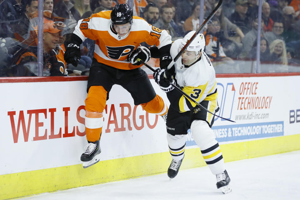 FILE - In this Jan. 21, 2020, file photo, Philadelphia Flyers' Tyler Pitlick, left, tries to jump past Pittsburgh Penguins' Jack Johnson during the second period of an NHL hockey game in Philadelphia. The latest chapter of The Battle of Alberta is on hold. So's the potential renewal of the Pennsylvania rivalry between the Penguins and Flyers. It's unclear when or if the coronvirus pandemic-delayed NHL playoffs -- which were supposed to begin Wednesday -- will be played or what form they'll resemble. (AP Photo/Matt Slocum, FIle)