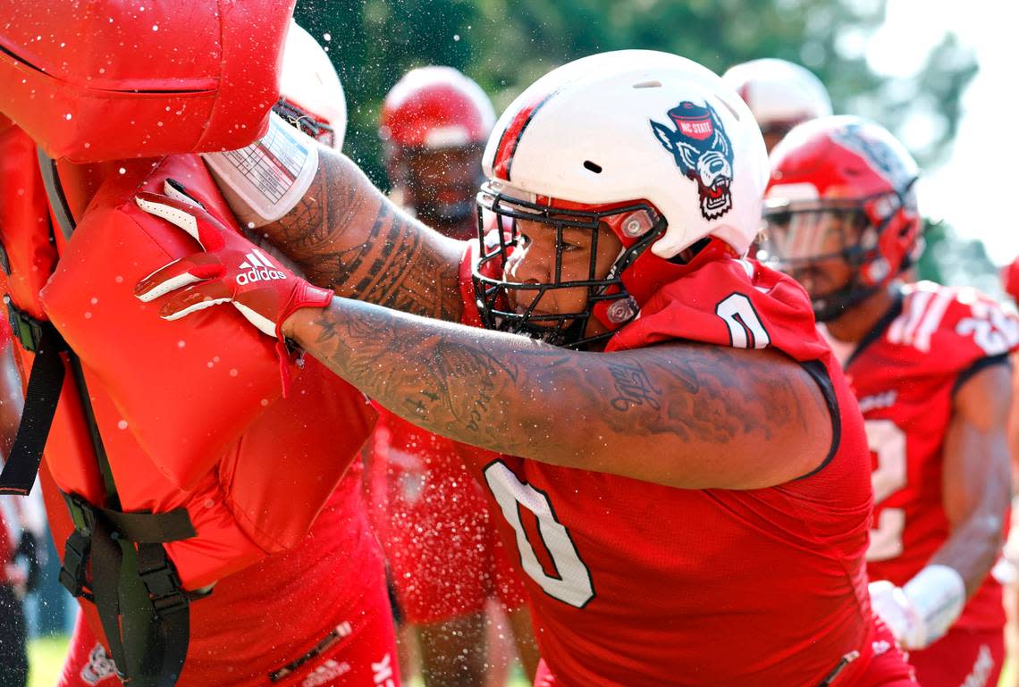 Sweat flies off N.C. State defensive tackle Joshua Harris (0) as he runs a drill during the Wolfpack’s first practice of fall camp in Raleigh, N.C., Wednesday, August 3, 2022.