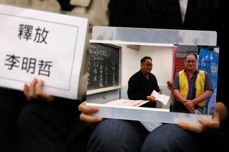 Li Ching-yu (R), wife of Taiwanese human right activist Li Ming-che, detained in China, holds photos of her husband at a news conference in Taipei, Taiwan March 29, 2017. REUTERS/Tyrone Siu