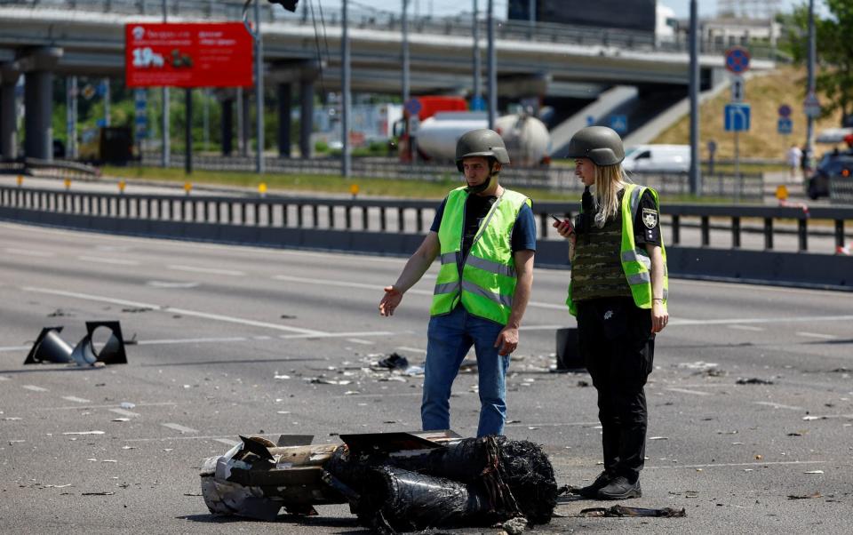 Police officers stand next to a part of a missile which landed on a street during a Russian strike in Kyiv - VALENTYN OGIRENKO/REUTERS