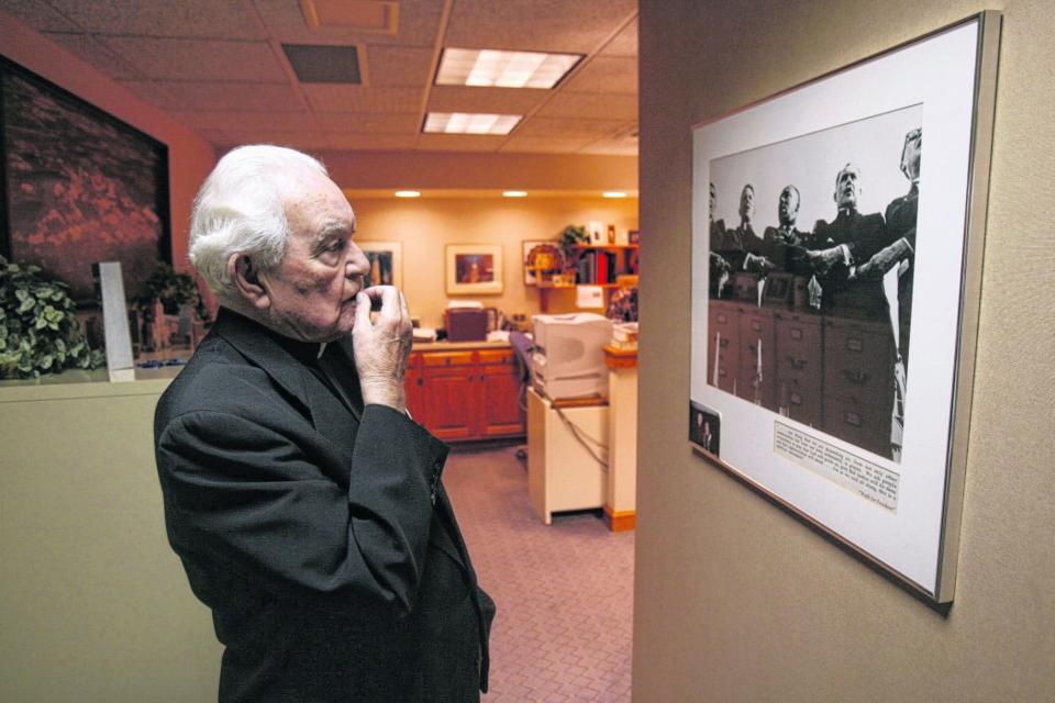 In this May 15, 2007, file photo, the Rev. Theodore M. Hesburgh, president emeritus of the University of Notre Dame, reflects on a photo showing him joining hands with the Rev. Martin Luther King Jr. at Soldier Field in Chicago at the Walk for Freedom Civil Rights March on June 21, 1964.