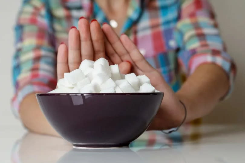 Woman refuses a bowl filled with sugar cubes