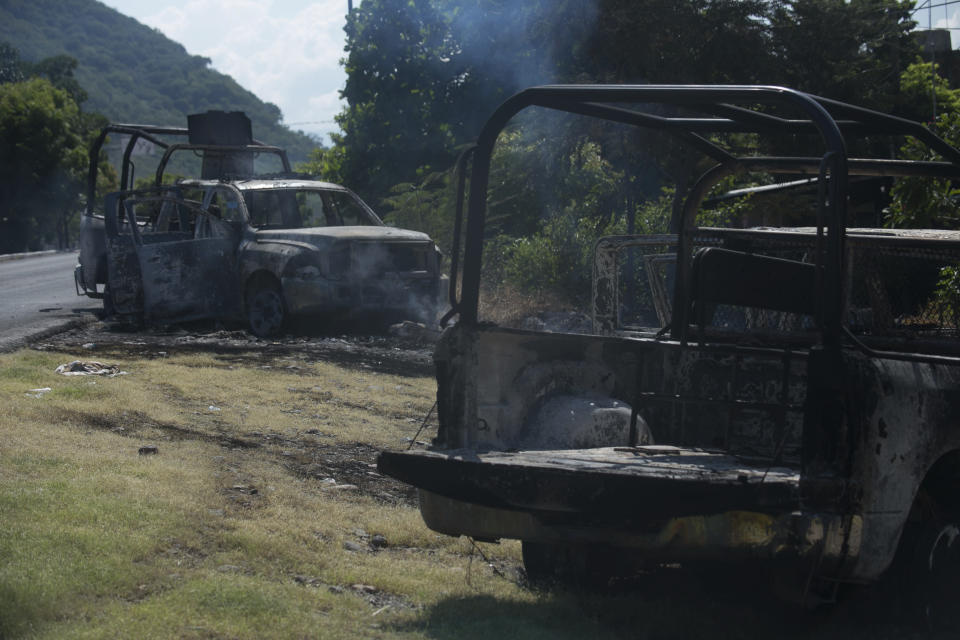 Charred trucks that belong to the Michoacan state police stand on the roadside after they were attacked in El Aguaje, Mexico, Monday, Oct. 14, 2019. At least 13 police officers were killed and nine others injured in the ambush. (AP Photo/Armando Solis)