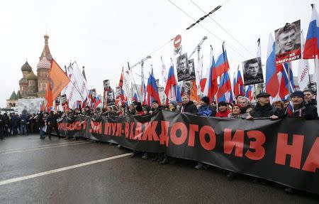 People march behind a banner to commemorate Kremlin critic Boris Nemtsov, who was shot dead on Friday night, with St. Basil's Cathedral seen in the background, in central Moscow March 1, 2015. The banner reads, "Heroes don't die". REUTERS/Sergei Karpukhin