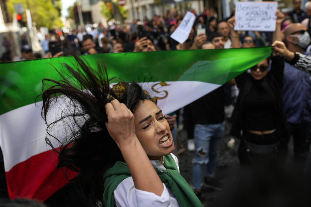 A woman shouts slogans next to an Iranian flag during a protest against the death of Iranian Mahsa Amini, outside Iran's general consulate in Istanbul, Turkey, Wednesday, Sept. 21, 2022. Protests have erupted across Iran in recent days after Amini, a 22-year-old woman, died while being held by the morality police for violating the country's strictly enforced Islamic dress code. (AP Photo/Francisco Seco)
