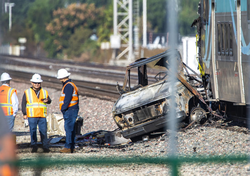 Investigators work at the scene after an RV was hit by a commuter train and burst into flames along a track in Santa Fe Springs, Calif., Friday, Nov. 22, 2019. Authorities say the collision occurred shortly after 5:30 a.m. Friday at an intersection in an industrial area of Santa Fe Springs. There were no immediate reports of injuries. All passengers on the Metrolink train were safely evacuated. (Mark Rightmire/The Orange County Register via AP)