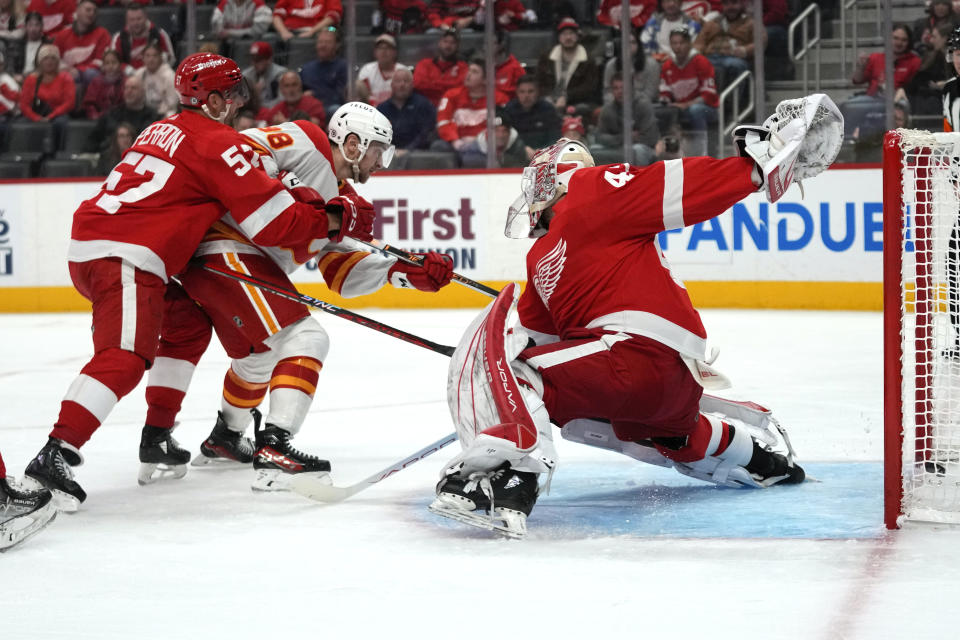 Calgary Flames left wing Andrew Mangiapane (88) scores on Detroit Red Wings goaltender James Reimer (47) as David Perron (57) defends in the second period of an NHL hockey game Sunday, Oct. 22, 2023, in Detroit. (AP Photo/Paul Sancya)