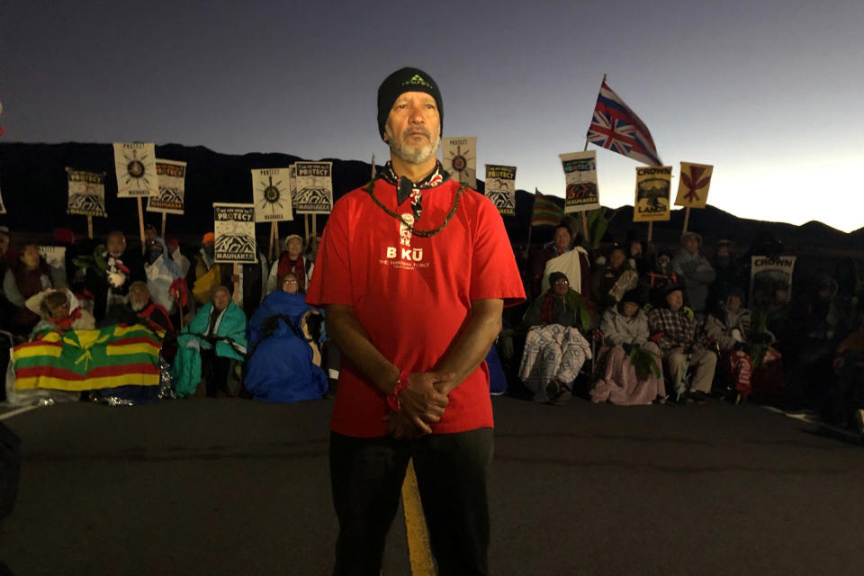 Dexter Kaiama, center, joins demonstrators gathered to block a road at the base of Hawaii's tallest mountain, Monday, July 15, 2019, in Mauna Kea, Hawaii, to protest the construction of a giant telescope on land that some Native Hawaiians consider sacred. (AP Photo/Caleb Jones)