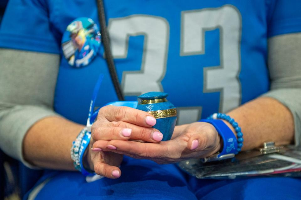 Megan Stefanski holds her father Donnie "Yooperman" Stefanski's ashes while sitting in the stands before the start of the game against the L.A. Rams at Ford Field on Sunday, Jan. 14, 2023.