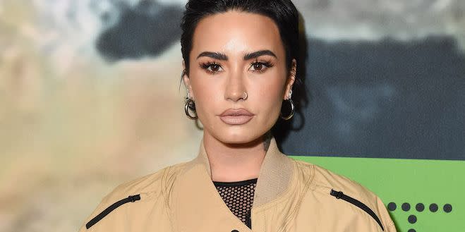 demi lovato at the adidas x stella mccartney launch event with slicked back hair and a beige bomber jacket on