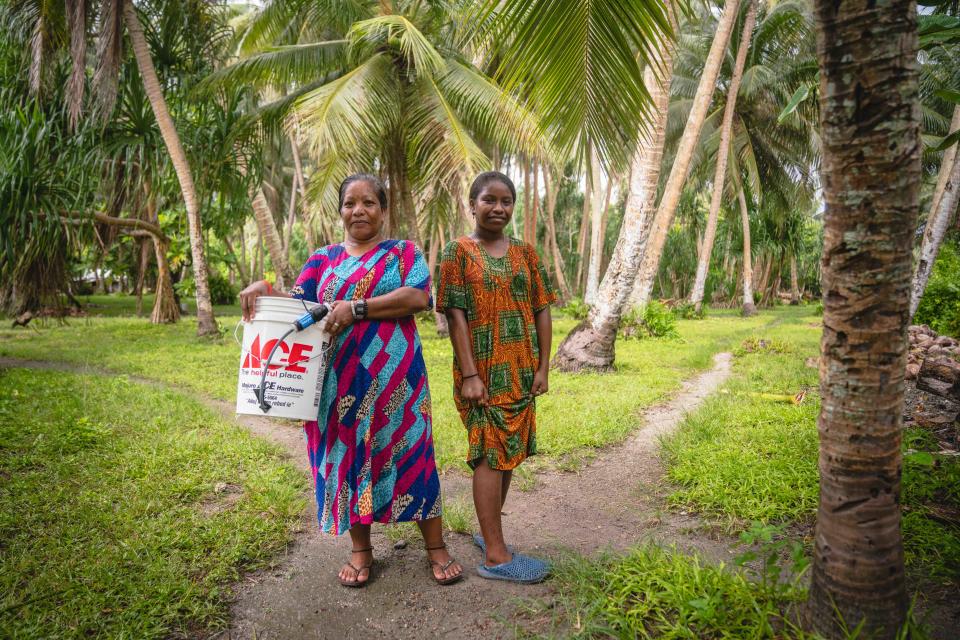 A Marshall Islands family with their new water filtration system, including a Sawyer filter and bucket.