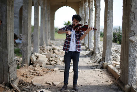 Ameen Mukdad, un violinista de Mosul que vivió bajo el régimen de Estado Islámico por dos años y medio y sufrió la destrucción de sus instrumentos musicales, realiza un pequeño concierto en el santuario de Nabi Yunus en el este de Mosul, Irak, 19 de abril de 2017. En medio de las ruinas bombardeadas de un antiguo lugar venerado por musulmanes y cristianos en Mosul, el violinista iraquí Ameen Mukdad realizó el miércoles un pequeño concierto en la ciudad de la que huyó obligado por milicianos de Estado Islámico. REUTERS/Muhammad Hamed