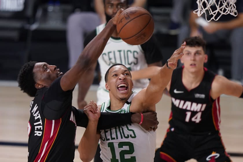 Miami Heat's Bam Adebayo, left, and Boston Celtics' Grant Williams (12) battle for a rebound during the second half of an NBA conference final playoff basketball game Sunday, Sept. 27, 2020, in Lake Buena Vista, Fla. (AP Photo/Mark J. Terrill)