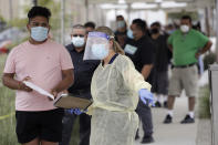 FILE - In this July 22, 2020 file photo, people line up behind a health care worker at a mobile Coronavirus testing site at the Charles Drew University of Medicine and Science in Los Angeles. A technical problem has caused a lag in California's tally of coronavirus test results, casting doubt on the accuracy of recent data showing improvements in the infection rate and number of positive cases, and hindering efforts to track the spread, the state's top health official said Tuesday, Aug. 4, 2020. (AP Photo/Marcio Jose Sanchez, File)