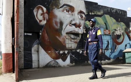 A security guard walks past a wall mural depicting U.S. President Barack Obama outside the Go-Down Art Centre in Kenya's capital Nairobi, July 17, 2015. REUTERS/Thomas Mukoya