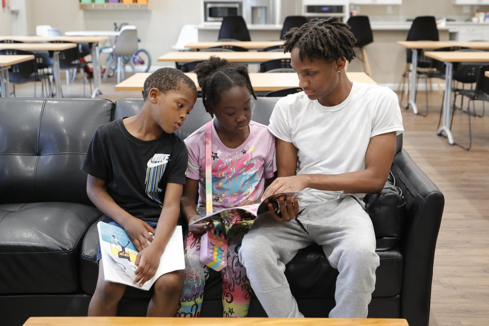 Karter Hardeman, 7, left, and Janayla Ralsey, 8, center, read with volunteer Joshua Banks, right, during an after-school literacy program in Atlanta on Thursday, April 6, 2023. The after-school program is open to students in kindergarten through fifth grade through the Atlanta based Pure Hope Project. (AP Photo/Alex Slitz)