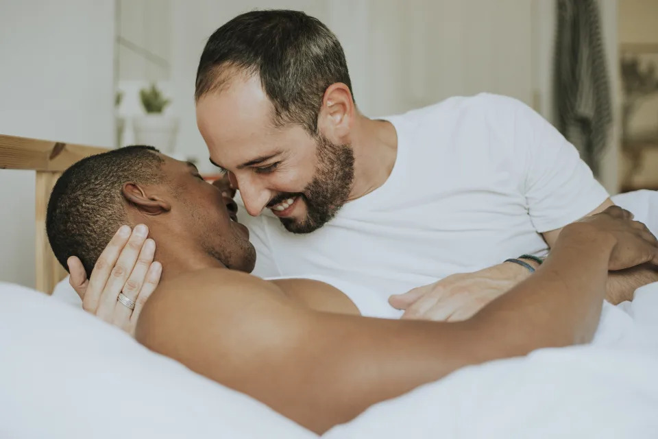 Gay couple in bed demonstrating improved mental health