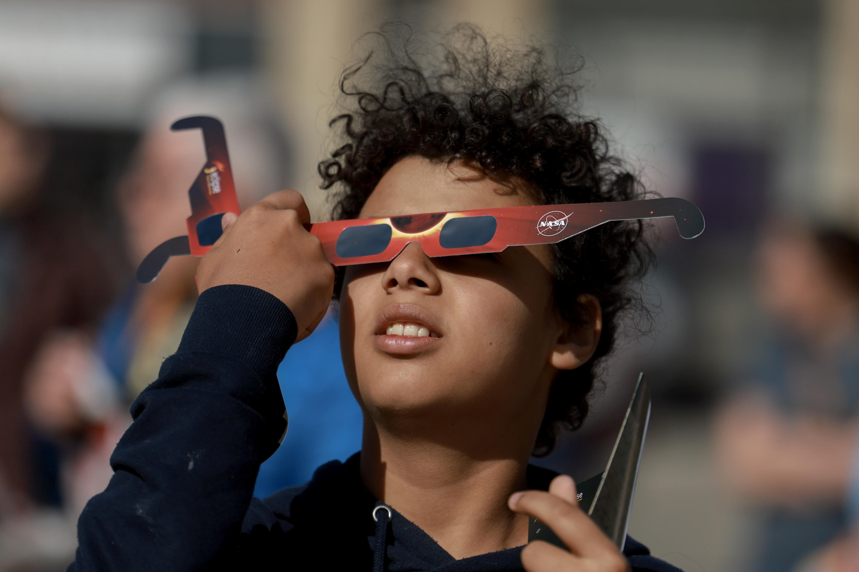 Junior Espejo looks through eclipse glasses being handed out by NASA in Houlton, Maine.