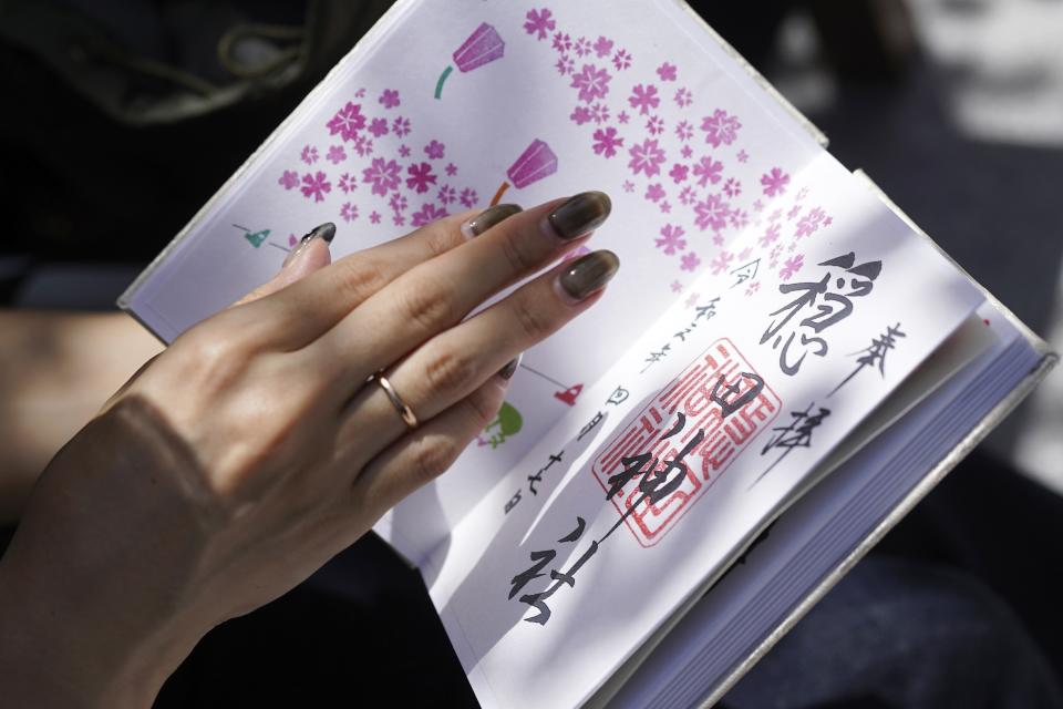 Momo Nomura, a graphic artist and entrepreneur, speaks on her collection of Goshuin, a seal stamp certifying her visit that comes with elegant calligraphy and the season’s drawings, at Sakura Jingu shrine in Tokyo on Aug. 30, 2023. Nomura began collecting the stamps during the pandemic. (AP Photo/Eugene Hoshiko)