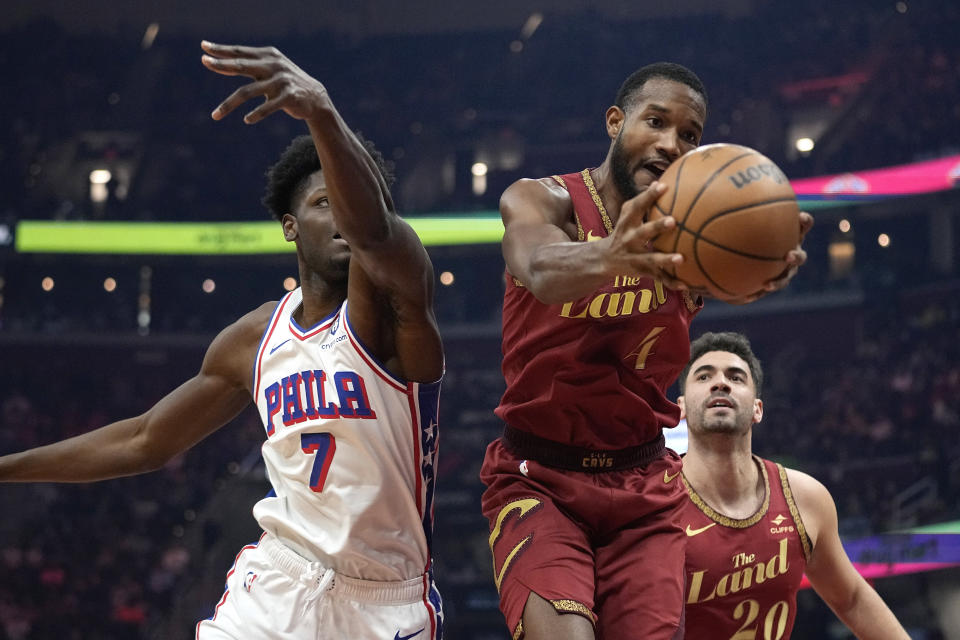 Cleveland Cavaliers forward Evan Mobley (4) grabs a rebound in front of Philadelphia 76ers center Mo Bamba (7) and teammate Georges Niang (20) in the first half of an NBA basketball game, Monday, Feb. 12, 2024, in Cleveland. (AP Photo/Sue Ogrocki)
