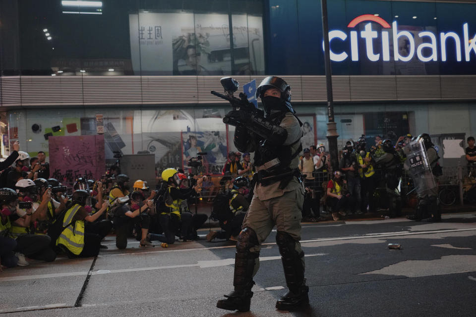 A Hong Kong police officer holds a weapon during confrontation with protesters in Hong Kong Sunday, Oct. 27, 2019. Hong Kong police fired tear gas Sunday to disperse a rally called over concerns about police conduct in monthslong pro-democracy demonstrations, with protesters cursing the officers and calling them "gangster cops." (AP Photo/Vincent Yu)