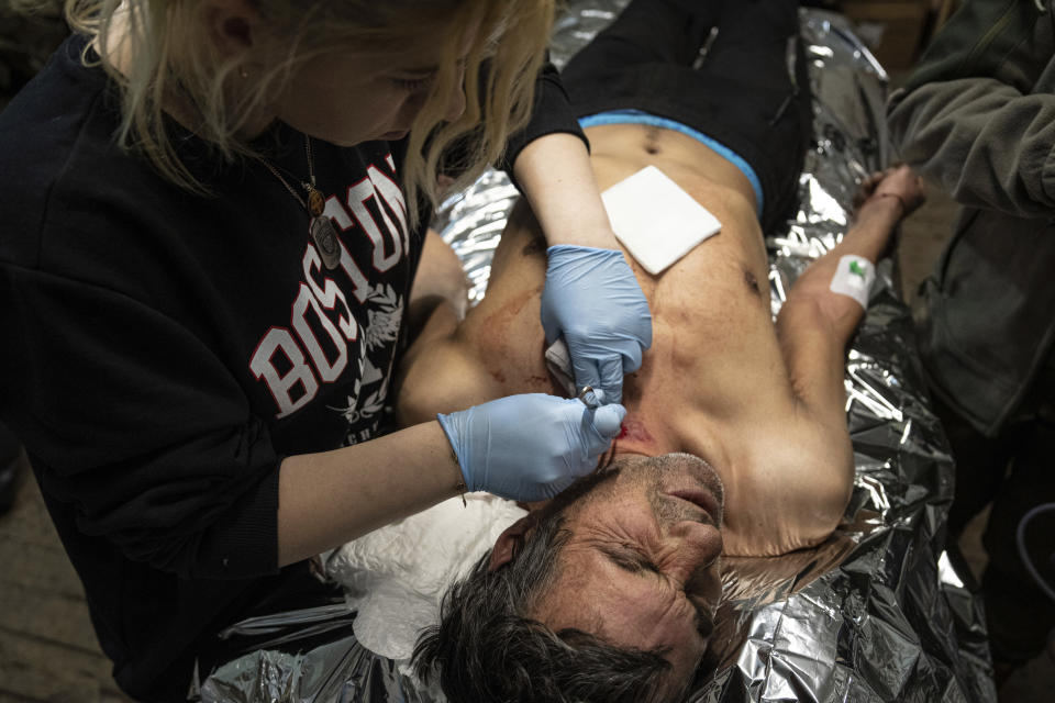 A Ukrainian military medic treats her wounded comrade at the field hospital near Bakhmut, Ukraine, Sunday, Feb. 26, 2023. (AP Photo/Evgeniy Maloletka)