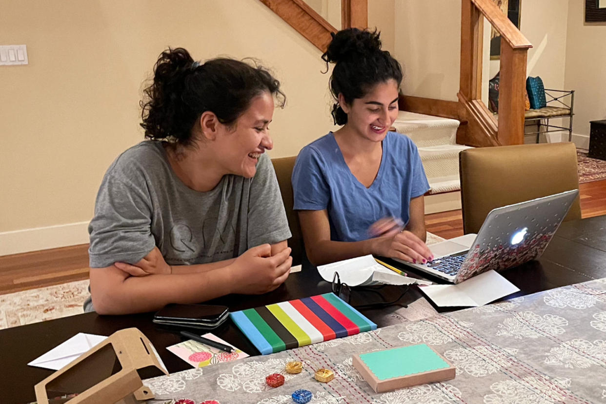 Sola Mahfouz and Malaina Kapour siting at a table and looking at a laptop. (Courtesy Sola Mahfouz and Malaina Kapour)