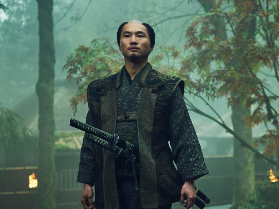 hiroto kanai as kashigi omi, a young main with two katana swords strapped to his waist, and a head shaven on the top with neat facial hair