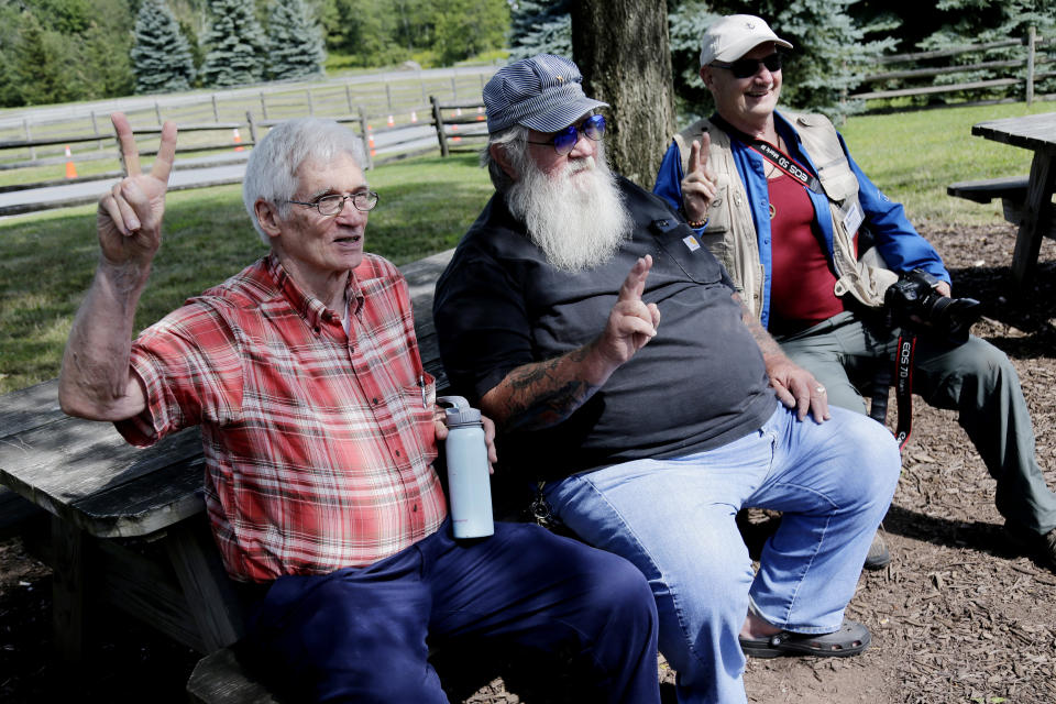 Woodstock veterans Roger Dennis, left, Duke Devlin, center, and Joe Klimasiewfski pose for a picture at the original site of the 1969 Woodstock Music and Arts Fair in Bethel, N.Y., Thursday, Aug. 15, 2019. Woodstock fans are expected to get back to the garden to mark the 50th anniversary of the generation-defining festival. Bethel Woods Center for the Arts is hosting a series of events Thursday through Sunday at the bucolic 1969 concert site, 80 miles (130 kilometers) northwest of New York City. (AP Photo/Seth Wenig)