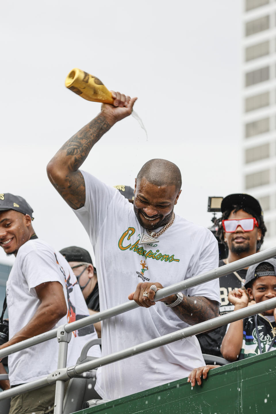 Milwaukee Bucks' P.J. Tucker holds a bottle of champagne during a parade and celebration for the NBA Championship Bucks basketball team Thursday, July 22, 2021, in Milwaukee. (AP Photo/Jeffrey Phelps)