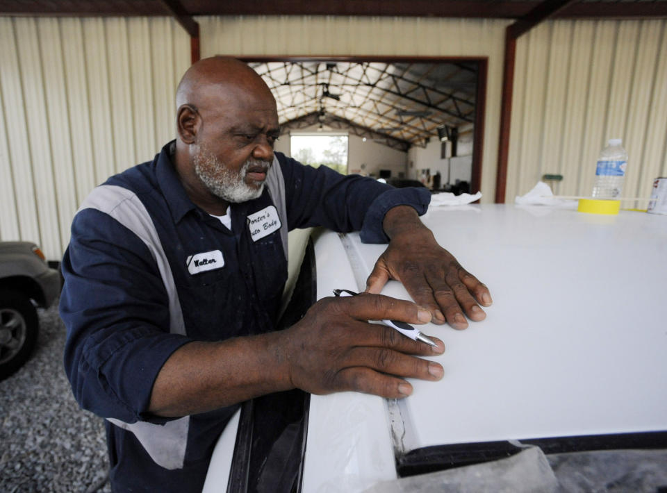 In this Tuesday, July 9, 2019 photo, Walter Porter, Mayor of Epes, Ala., works on a vehicle at his automotive body shop in Epes. The town is still poor despite having a port along the 234-mile-long Tennessee-Tombigbee Waterway, and Porter said dreams of development from the $2 billion project remain unfulfilled more than three decades after it opened. (AP Photo/Jay Reeves)