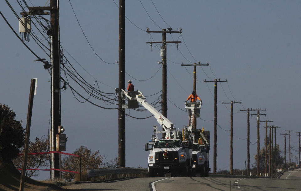 FILE - In this Nov. 25, 2018 file photo Utility crews repair overhead lines along Pacific Coast Highway just west of Malibu, Calif., where the Woolsey Fire burned down from the Santa Monica Mountains to the water's edge at Leo Carrillo State Beach. Southern California Edison announced in its quarterly earnings report that its equipment probably caused the November 2018 Woolsey Fire that raged from north of Los Angeles through Malibu to the sea, killing three people and burning more than 1,600 homes and other buildings. (AP Photo/John Antczak,File)