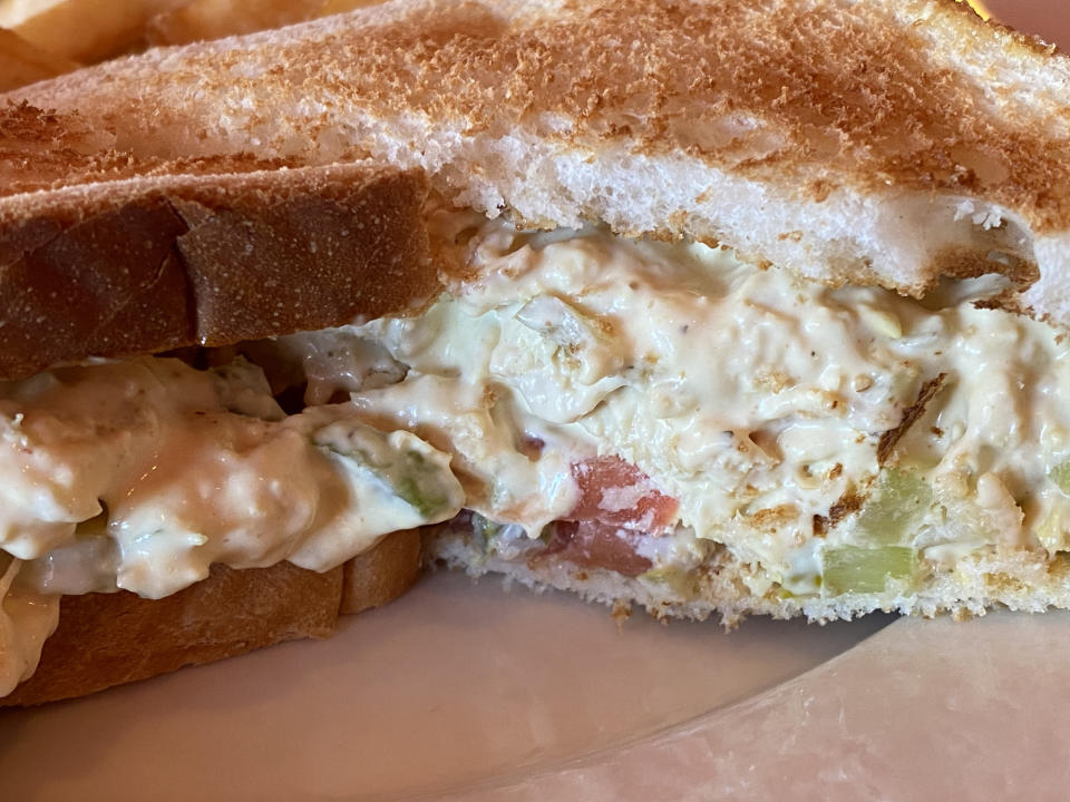 Close-up of a toasted sandwich with a creamy filling containing visible pieces of vegetables