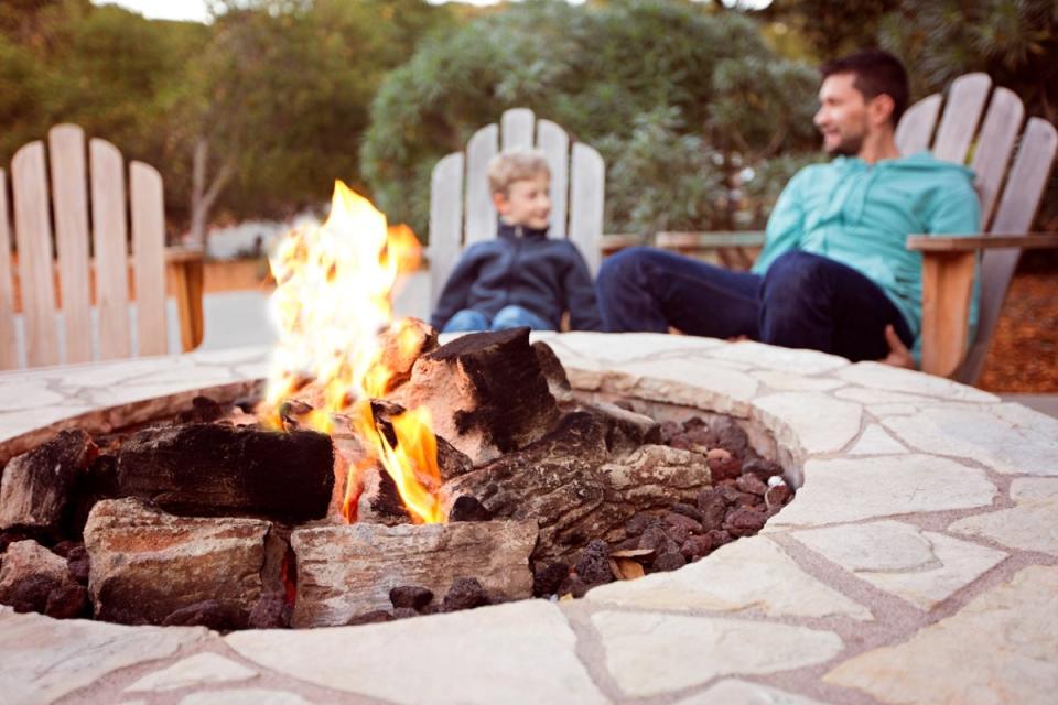 Father and son in Adirondack chairs behind fire pit