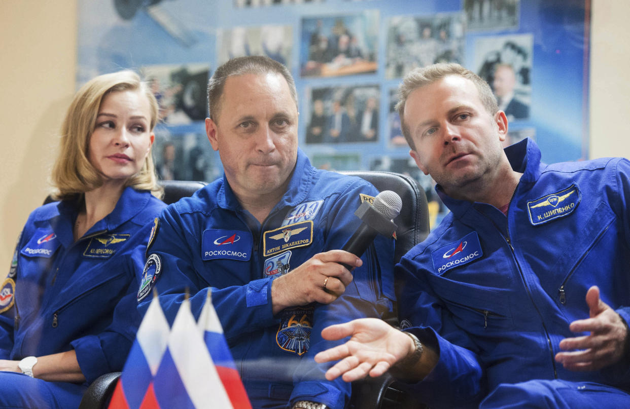 In this handout photo released by Roscosmos, actress Yulia Peresild, left, director Klim Shipenko, right, and cosmonaut Anton Shkaplerov, members of the prime crew of Soyuz MS-19 spaceship attend a news conference at the Russian launch facility in the Baikonur Cosmodrome, Kazakhstan, Monday, Oct. 4, 2021. In a historic first, Russia is set to launch an actress and a film director to space to make a feature film in orbit. Actress Yulia Peresild and director Klim Shipenko are set to blast off Tuesday for the International Space Station in a Russian Soyuz spacecraft together with Anton Shkaplerov, a veteran of three space missions.(Roscosmos Space Agency via AP)