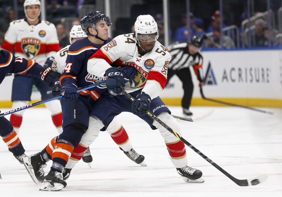 New York Islanders center Jean-Gabriel Pageau, left, checks Florida Panthers forward Givani Smith during the first period of an NHL hockey game Friday, Dec. 23, 2022, in Elmont, N.Y. (AP Photo/John Munson)