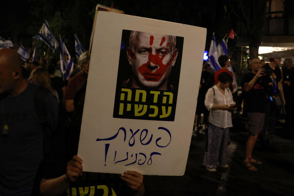 Protesters hold a sign depicting Israeli Prime Minister Benjamin Netanyahu with words reading, 