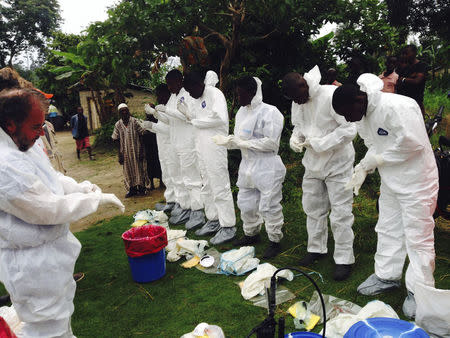 Volunteers prepare to remove the bodies of people who were suspected of contracting Ebola and died in the community in the village of Pendebu, north of Kenema July 18, 2014. REUTERS/WHO/Tarik Jasarevic