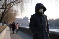 People wearing protective masks walk outside Forbidden City which is closed to visitors, according to a notice in its main entrance for the safety concern following the outbreak of a new coronavirus, in Beijing