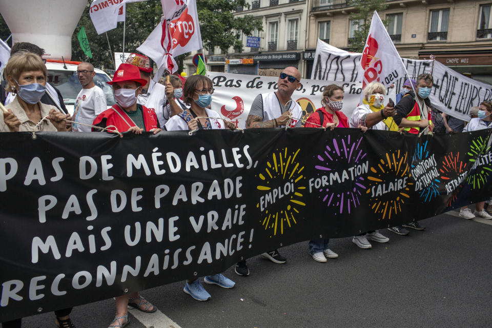 Hospital workers demonstrate during Bastille Day in Paris, Tuesday, July 14, 2020.French hospital workers are protesting to demand better pay and more investment in France's public hospital system, which is considered among the world's best but struggled to handle a flux of virus patients after years of cost cuts. Banner in French reads: "no medals, no parade, but real recognition"(AP Photo/Rafael Yaghobzadeh)