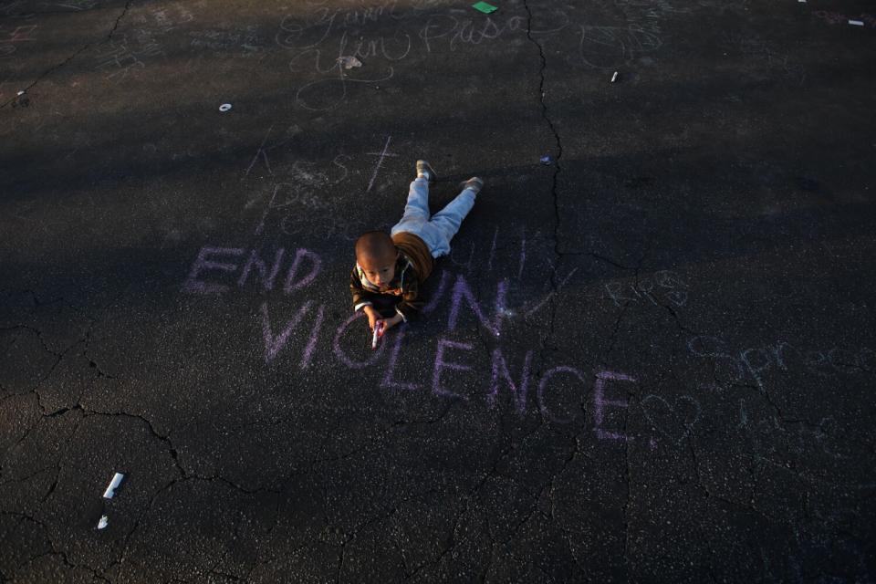 Harry Su, 2, lays on the message, "End Gun Violence," at the memorial for 11 people who died in a mass shooting.