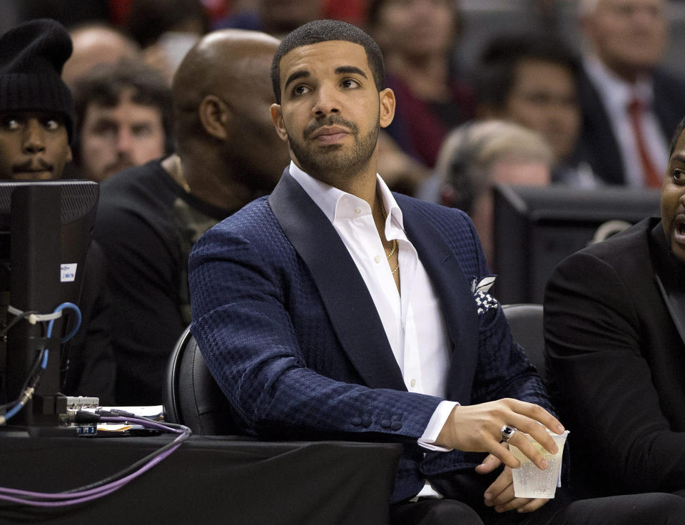 Drake keeps an eye on the action during the second half of a preseason NBA basketball game as the Toronto Raptors play against the Memphis Grizzlies in Toronto on Wednesday, Oct. 23, 2013. (AP Photo/The Canadian Press, Frank Gunn)