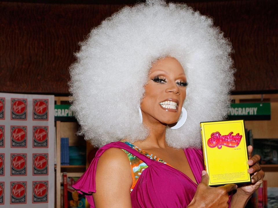 Rupaul in drag holding up book