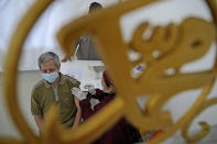 A man is seen through a mosque ornament in Arabic writing that reads: "Muhammad" as he receives a shot of the AstraZeneca vaccine for COVID-19 during a mass vaccination in Depok on the outskirts of Jakarta, Indonesia, Saturday, June 19, 2021. Indonesia, the world's fourth most populous country, aims to inoculate more than 181 million of its 270 million people by March 2022 but progress have been slow due to limited global vaccine supply, the unpreparedness of the national health system and vaccine hesitancy. (AP Photo/Dita Alangkara)