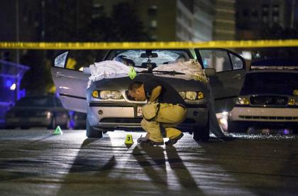 Boston Police investigate a car in which Daniel de Abreu and Safiro Furtado were shot to death. (AP)