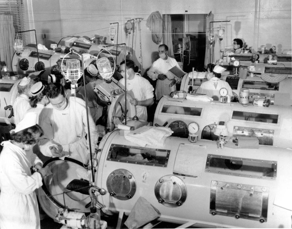 This is a scene in the emergency polio ward at Haynes Memorial Hospital in Boston in 1955, showing critical victims lined up in iron lung respirators. The coffin-like devices helped those whose bodies were crippled by polio breathe artificially. Later in 1955, Jonas Salk discovered the vaccine for polio, which today has been eradicated from all but three countries.